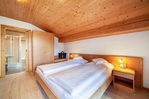 拉貢多的住宿－Rasnerhof Ferienwohnung Panorama，一间卧室设有一张带木制天花板的大床
