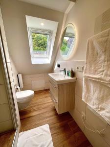 a bathroom with a sink and a toilet and two windows at Sky Apartment, Sauna, Blick zur Mosel, großer Balkon, Kaffeemaschine, Smart TV in Zell an der Mosel