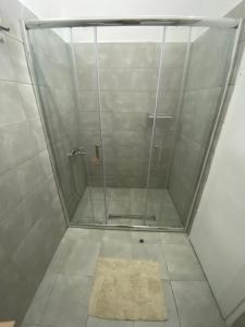 a shower stall with a glass door and a rug at Apartmani Home in Zaječar