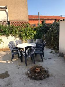 um pátio com uma mesa e cadeiras e uma fogueira em Grande maison de ville avec jardin T7 perpignan em Perpignan