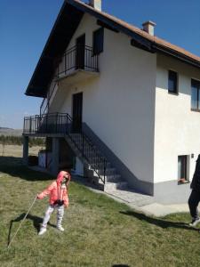 un niño pequeño jugando con una cometa delante de un edificio en Apartman Teodora Uvac en Nova Varoš