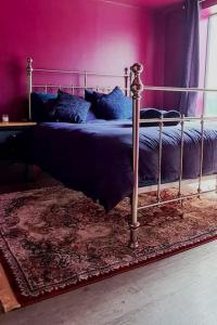 a bed in a bedroom with a purple wall at The Wolf's Den in Patrington