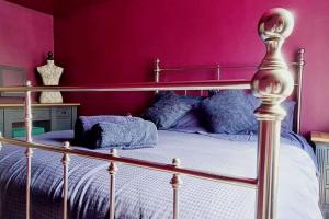 a bedroom with a bed with a pink wall at The Wolf's Den in Patrington