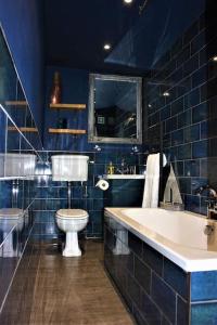 a blue bathroom with a toilet and a sink at The Wolf's Den in Patrington