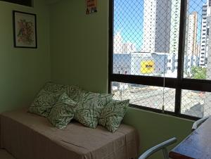 uma cama com almofadas num quarto com uma janela em Cantinho Aconchegante 306 Praia - Tambaú 2 em João Pessoa