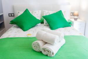 Romántico Estudio con Piscina في مالقة: غرفة نوم مع وسائد ومناشف خضراء على سرير