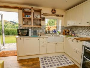 a kitchen with a sink and a microwave at Buzzards Breg in Builth Wells