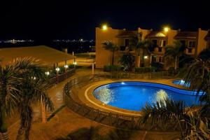 a swimming pool in front of a house at night at Alahlam Resort Yanbu in Yanbu