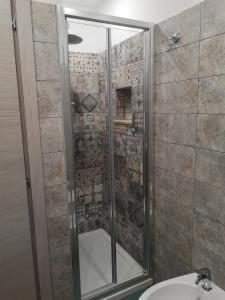 a shower with a glass door next to a sink at Le Cassiere DNA in Roccalumera