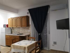 a kitchen with a table and a kitchen with a table and a television at Le Cassiere DNA in Roccalumera