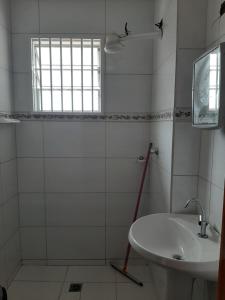 a white bathroom with a sink and a window at Casa em Matinhos PR in Matinhos