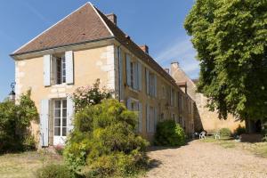 een oud bakstenen gebouw met een boom ervoor bij Charming Normandy Country Home in Condeau