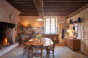 een keuken met een tafel en stoelen en een open haard bij Charming Normandy Country Home in Condeau