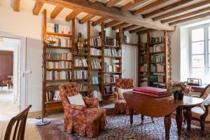 een woonkamer met een tafel en stoelen en boekenplanken bij Charming Normandy Country Home in Condeau