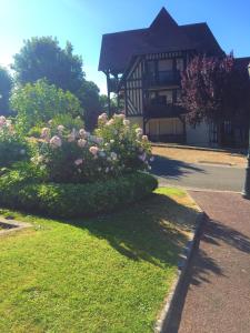 a house with a bush of flowers in the yard at Domaine privé, , piscine, jacuzzi, joli appartement in Deauville