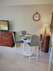a dining room with a table and chairs and a clock at Domaine privé, , piscine, jacuzzi, joli appartement in Deauville