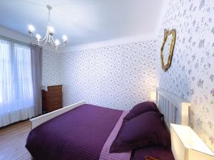 a bedroom with a purple bed and a chandelier at Biarritz-Anglet Appartement T3 en villa jumelle in Anglet