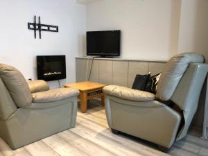 a living room with two chairs and a tv at Sweet Caroline at Longton. Great location for Stoke on Trent, The Potteries and Alton Towers. in Longton