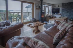 a living room with a leather couch and a fireplace at Bayview House - 4 Bedroom Luxurious Holiday Home - Saundersfoot in Saundersfoot