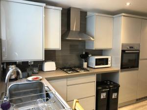a kitchen with white cabinets and a sink and a microwave at Sweet Caroline at Longton. Great location for Stoke on Trent, The Potteries and Alton Towers. in Longton