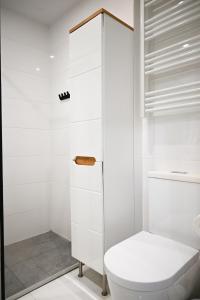 a white bathroom with a toilet and a shower at Apartamenty Morskie Moonlight Łukęcin in Łukęcin