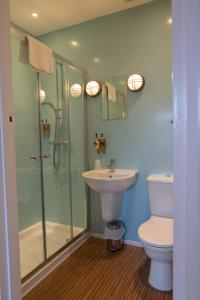 a bathroom with a shower and a sink and a toilet at The Randolph Hotel in Southwold