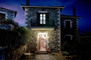 a stone house with a door with a light at night at Malevos Traditional Houses in Áyios Pétros