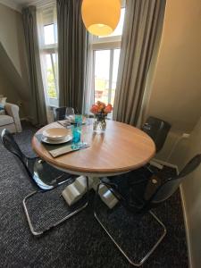 a dining room table with chairs and a table with flowers on it at Zentraler Altbaucharme mit Blick über die Stadt in Kiel +7 photos