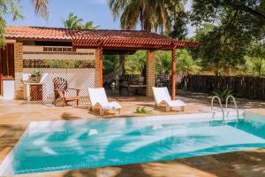 a swimming pool with two chairs and a gazebo at Refugios Parajuru - Chalet la Garagem in Parajuru