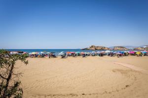 a group of people sitting on a beach with umbrellas at Nuevo apartamento en bahia de mazarron a estrenar in Murcia