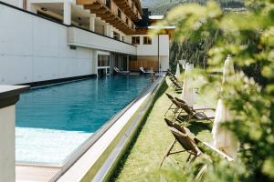 a swimming pool with lounge chairs and a swimming pool at Hotel Thurnerhof in Saalbach Hinterglemm