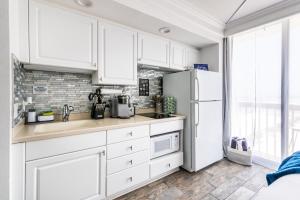 a kitchen with white cabinets and a refrigerator at Daytona Beach Resort - Ocean Front Luxury Studio in Daytona Beach