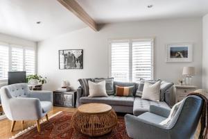 sala de estar con sofá, sillas y mesa en Kowhai Cottage & Studio, en Raglan