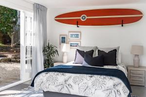 a surfboard hanging on the wall of a bedroom at Kowhai Cottage & Studio in Raglan