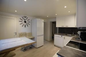a kitchen with a white refrigerator and a clock on the wall at Small cozy apartment by the sea in Havøysund