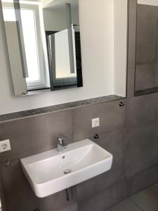 a white sink in a bathroom with two mirrors at Ferienwohnung Gabriel in Kirchentellinsfurt
