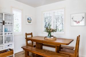 a dining room with a wooden table and chairs at Kowhai Cottage & Studio in Raglan