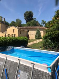a blue swimming pool in front of a house at Chateau du Vallier superbe suite vignobles BORDEAUX in Langoiran