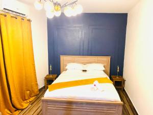 1 dormitorio con 1 cama con paredes azules y cortinas amarillas en Moya Résidence by MD en Dzaoudzi