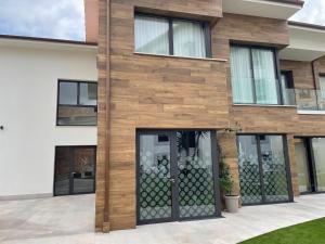 uma casa com uma fachada de madeira com portas de vidro em Apartamentos Las Indianas em Nueva de Llanes