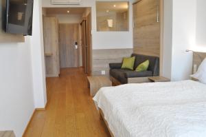 een slaapkamer met een bed en een woonkamer met een bank bij Seehotel Herlinde in Podersdorf am See