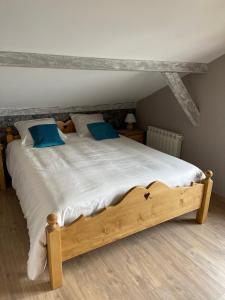 1 dormitorio con cama de madera y almohadas azules en CHALET-MICHEL avec SPA, en Montperreux