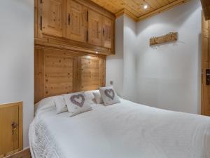 a bedroom with a white bed with wooden cabinets at Studio Méribel, 1 pièce, 4 personnes - FR-1-565-15 in Les Allues