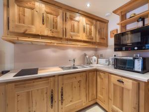 a kitchen with wooden cabinets and a sink and a microwave at Studio Méribel, 1 pièce, 4 personnes - FR-1-565-15 in Les Allues