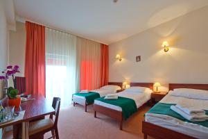 a hotel room with two beds and a desk at Hotel Kameralny in Kielce