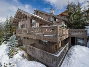 a wooden house with a deck in the snow at Chalet chaleureux avec jacuzzi, hammam et salle de jeux à Mussillon - FR-1-565-40 in Les Allues