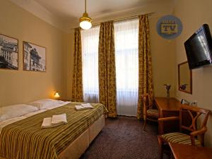 a bedroom with a bed, desk, chair and lamp at Anna Hotel in Prague