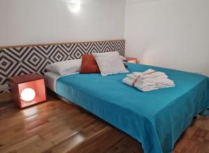 een slaapkamer met een bed met blauwe lakens en een lamp bij Design loft Rosella Home Sorrento in Piano di Sorrento
