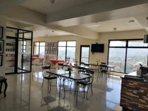 Habitación grande con mesas, sillas y ventanas. en 3 Pax Charming Foggy Cold Breeze, Cozy Gardenville Hotel, en Baguio