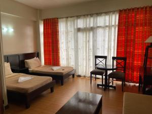 Sala de estar con 2 camas y mesa en 3 Pax Charming Foggy Cold Breeze, Cozy Gardenville Hotel, en Baguio
